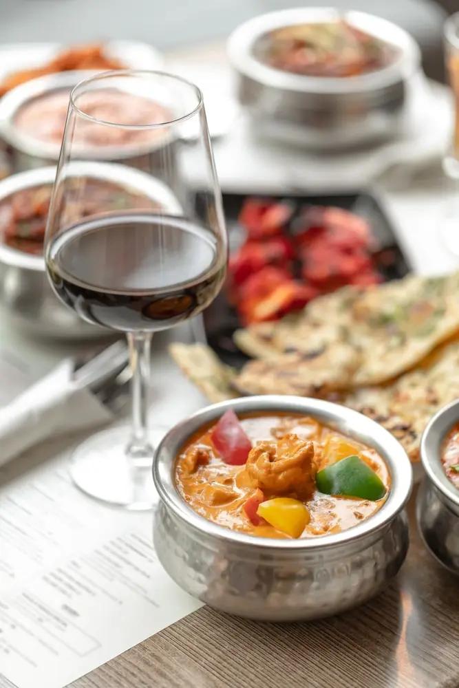 indian-cuisine-dish-with-a-glass-of-red-wine-on-a-restaurant-tab