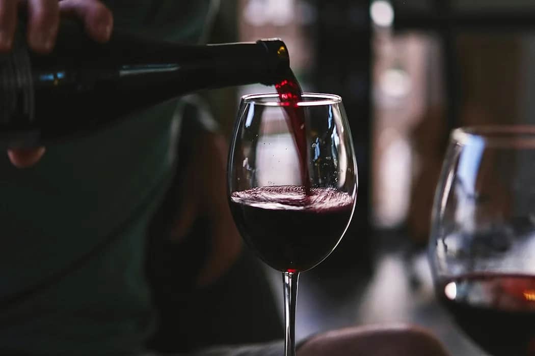 Omslagsbild till reportaget Vinets magi med vinflaskor och glas i varm belysning