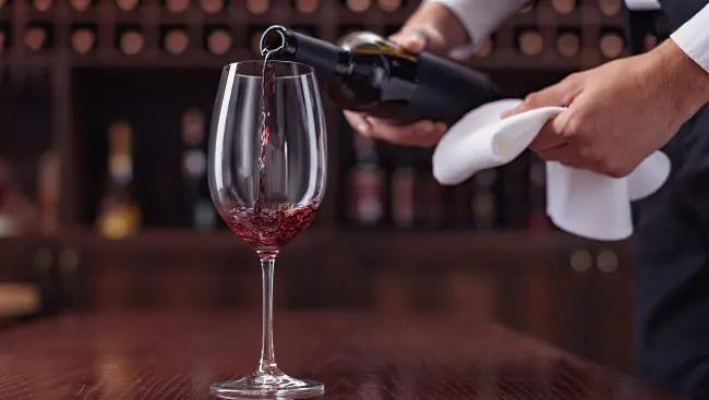 bordeaux-druvor-kypare-som-häller-upp-vin-i-glas