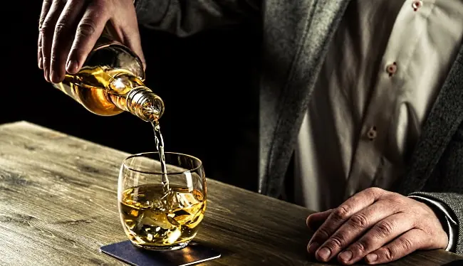 Japansk whisky - en man som häller upp whisky ur en flaska - Vinjournalen.se